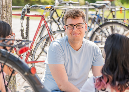 Kevin sitzt zwischen seinen Mitstudentinnen und Fahrrädern