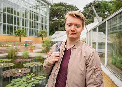 Domenik steht vor dem großen Seerosenteich im Botanischen Garten.