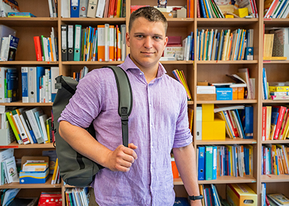 Leon steht vor einem Bücherregal.