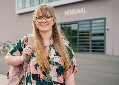 Paulina steht vor dem Hörsaalgebäude am Heide-Campus.