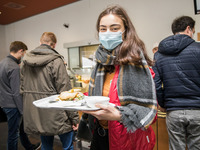 Eine Teilnehmerin steht in der Mensa mit einem Essenstablett in der Hand.