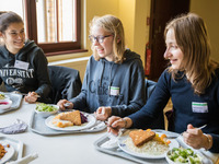 Zwei Schülerinnen und Mentorin Sophie unterhalten sich beim Essen in der Mensa
