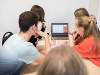 Schülerinnen und Schüler arbeiten an einem Laptop