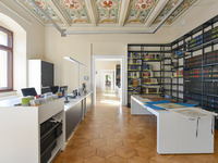 Blick große Arbeitsplätze, auf denen auch Karten studiert werden können. An der Seite befindet sich ein Tresen zur Medienausleihe. (Bild öffnet vergrößert)