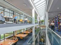 Links im Bild sieht man auf mehreren Etagen die Arbeitsplätze für Studierende, rechts stehen die Bücherregale. (Bild öffnet vergrößert)