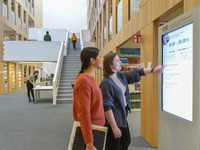 Zwei Studentinnen informieren und orientieren sich am digitalen Leitsystem.