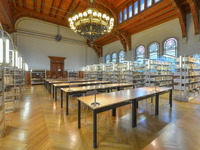 Blick in den historischen Lesesaal des IZEA. Der Raum wird von einem prunkvollen Kronleuchter beleuchtet, der an einer Holzdecke hängt. Die Bücherregale säumen den großzügigen Arbeitsbereich mit mehreren Tischen in der Mitte der Raumes.