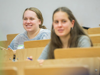 Zwei Teilnehmerinnen sitzen in einem Hörsaal und lächeln