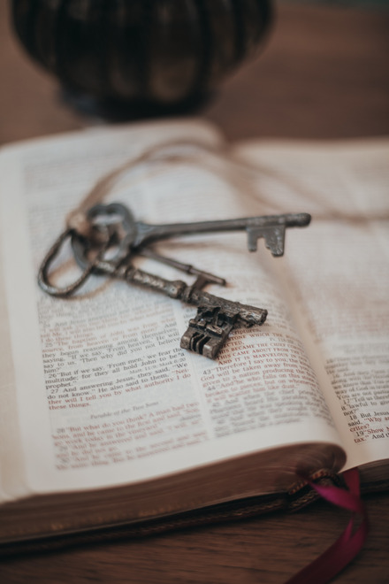 Auf dem Foto sieht man einen Schlüsselbund alter Messingschlüssel auf einem Buch liegen.