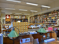 Blick in die Bibliothek der Altertumswissenschaften. Zwischen vielen Bücherregalen sieht man einige Büsten von Gelehrten stehen und in der Mitte einige Tische zum Arbeiten.