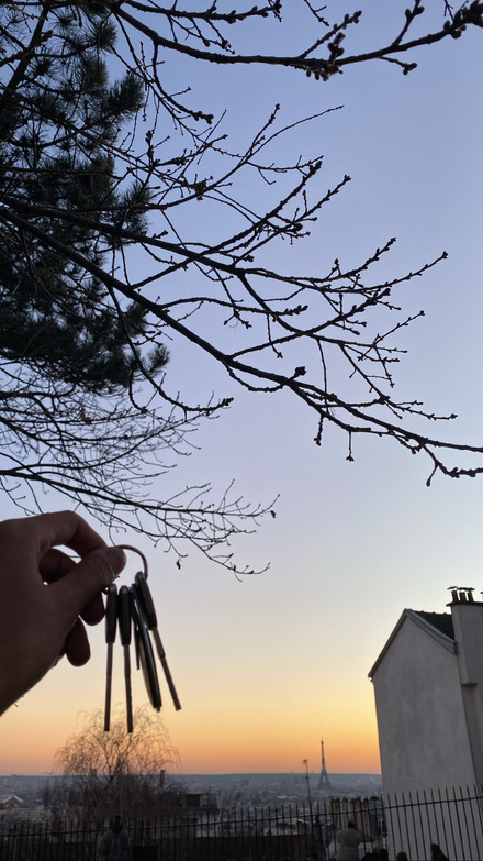 Die Schlüssel meiner neuen Wohnung in Montmartre mit dem Sonnenuntergang und dem Eiffelturm im Hintergrund