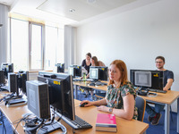 Studierende sitzen an Computern im großen Computer-Pool der Bibliothek.