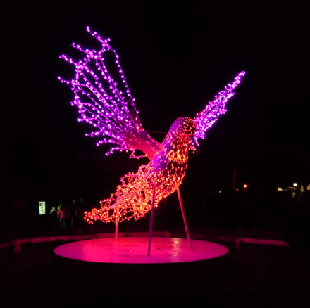 Zu sehen ist eine große in rot und lila leuchtende Lichtfigur in Form eines Vogels im Eingangsbereich des Leipziger Zoos.