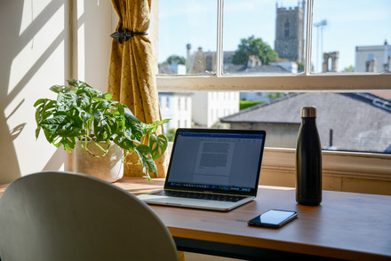 Foto: Ein Schreibtisch am Fenster mit schöner Aussicht über die Dächer. 