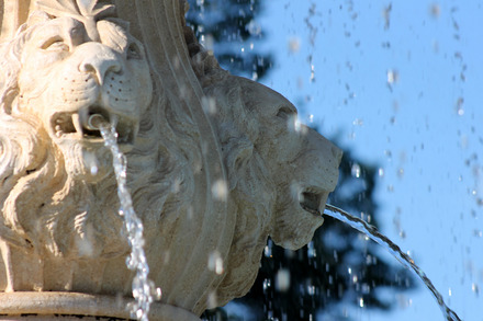 Zu sehen ist eine Fontäne aus Löwenköpfen, aus deren Münder Wasser fließt.