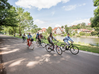 Junge Menschen radeln mit ihren Fahrrädern am Fluss entlang.