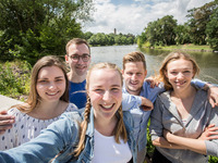 Studierende machen ein Selfie am Saaleufer. Im Hintergrund sieht man die Saale und die Burg Giebichenstein.