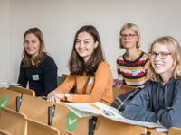 Vier Schülerinnen sitzen in einem Seminarraum und lächeln.