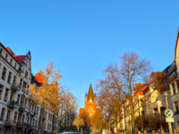 Foto: Eine der Straßen im Paulusviertel und im Hintergrund steht die wunderschöne Pauluskirche im Sonnenlicht. (Bild öffnet vergrößert)
