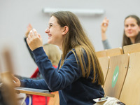 Eine Schülerin sitz lächelnd in einem Hörsaal der Universität.