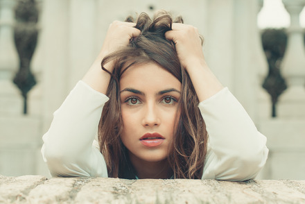 Auf dem Foto sieht man eine brünette, junge Frau, die sich die Haare rauft. Sie sieht verzweifelt aus.