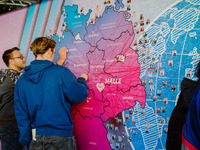 „Da komme ich her“ – Studierende markieren auf einer Aktionsfläche mit Deutschland- und Weltkarte ihren Heimatort. Zwei Studierende markieren mit einem Pin ihren Heimatort auf einer großen Deutschlandkarte. (Bild öffnet vergrößert)