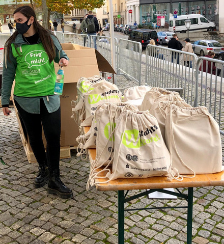 Auf dem Foto sieht man einen Tisch auf denen viele Jutesäcke liegen und eine junge Frau in grünem Leibchen.