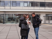 Foto: Zu sehen sind drei Personen, die im Halbkreis zueinander stehen. Hinter ihnen befindet sich das Fraunhofer Institut am Weinberg Campus.