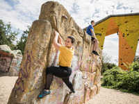Das Bild zeigt eine Studentin beim Klettern an einer öffentlich zugänglichen Kletterwand.
