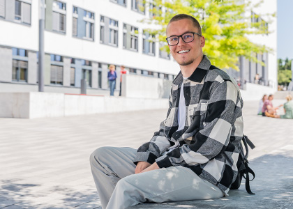 Foto: MLU / Matthias Ritzmann Julian sitzt auf dem Steintor Campus vor dem Hörsaalgebäude